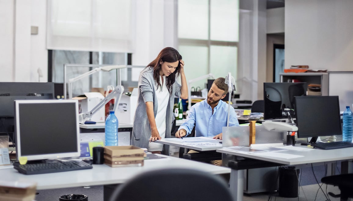 Two office workers are reviewing print results.